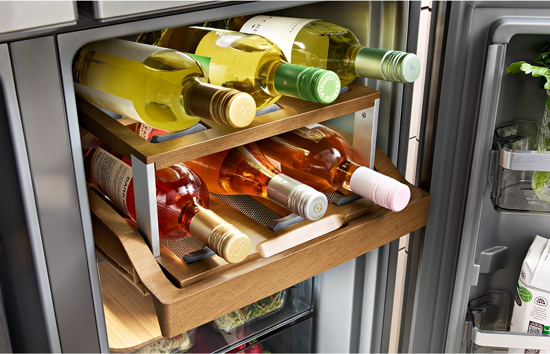 Wine bottles on a wooden sliding shelf inside of a KitchenAid® refrigerator