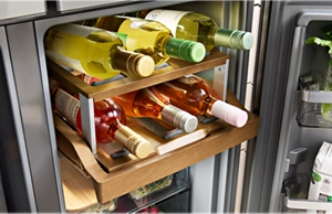 Wine bottles on a wooden sliding shelf inside of a KitchenAid® refrigerator