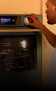 A person turning the dial on a KtichenAid® wall oven