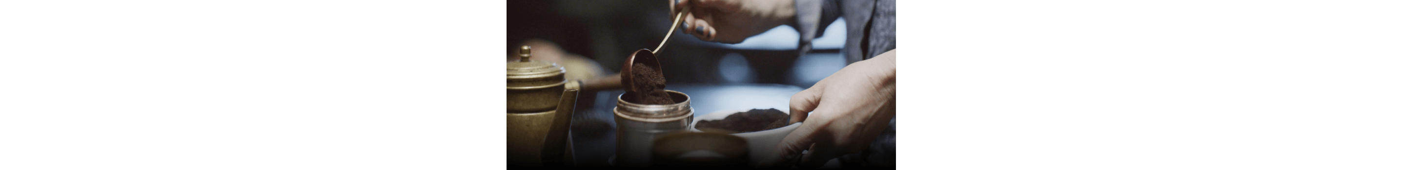 A person adding ground coffee into a bowl.