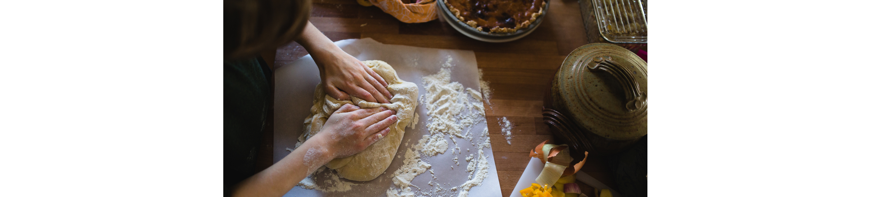 Strong hands working freshly made dough onto parchment paper.