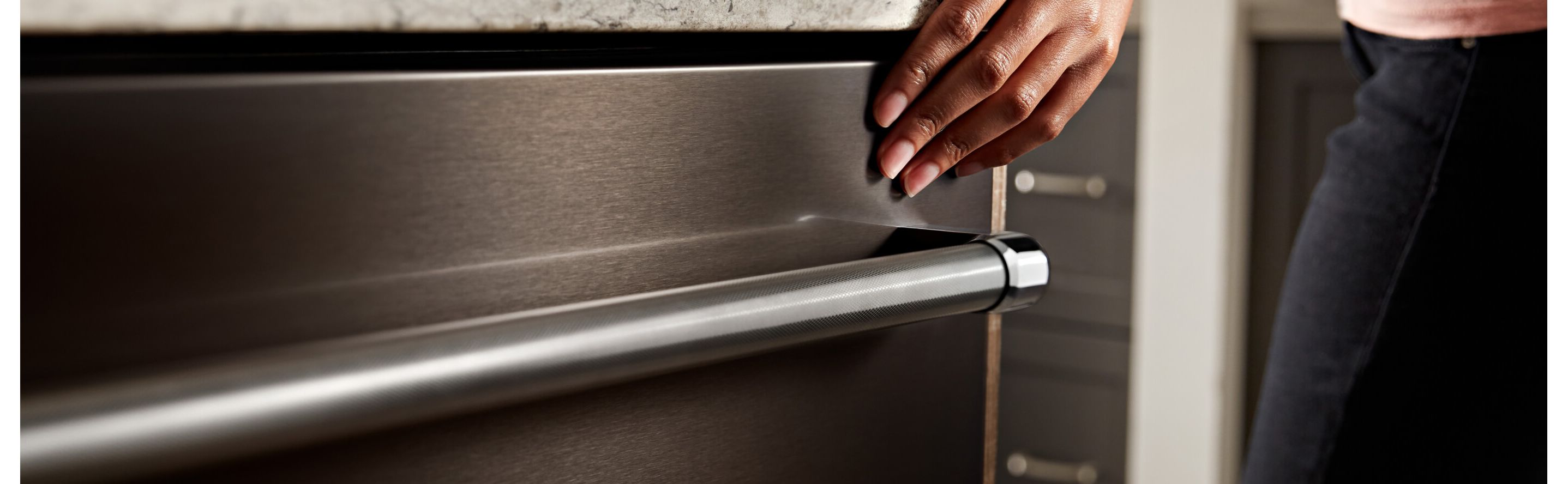 Hand closing a stainless steel dishwasher