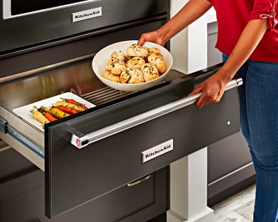 Person placing food in warming drawer