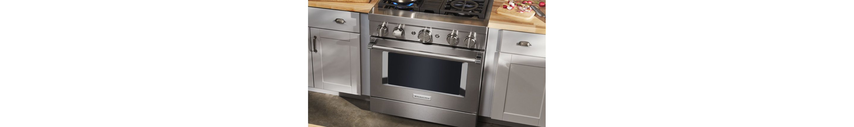 A KitchenAid® commercial-style range in a kitchen with white cabinets.