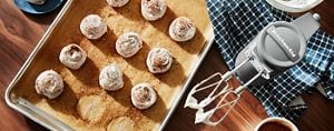Freshly-made meringues resting on parchment paper in a baking sheet.