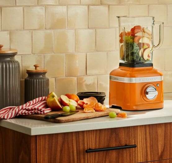 A K400 Variable Speed Blender in Honey filled with fruits and kale.