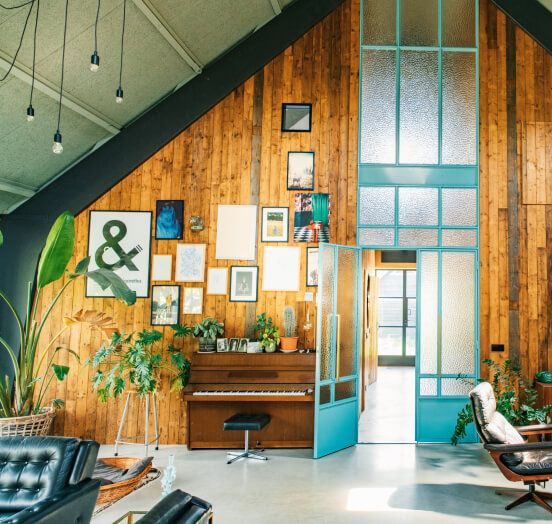 A bright office filled with wood accents, plants and leather furniture pieces.