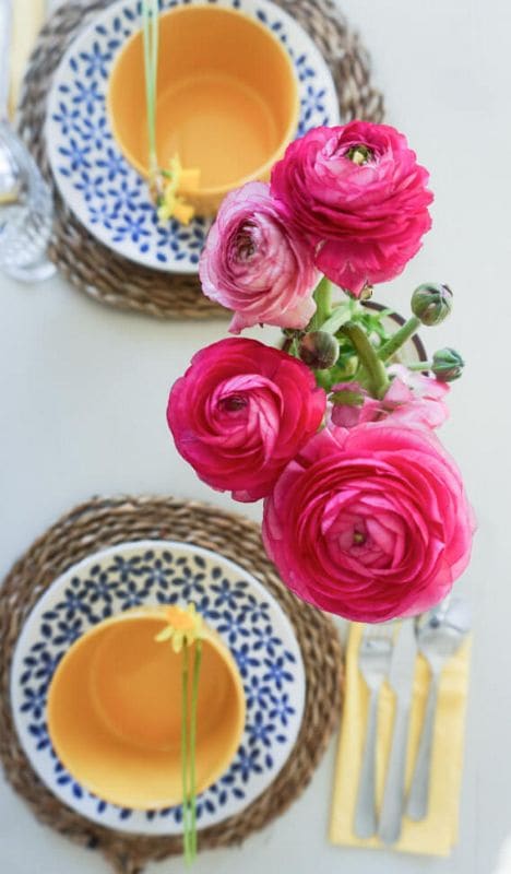 A set dinner table with large, pink flowers.