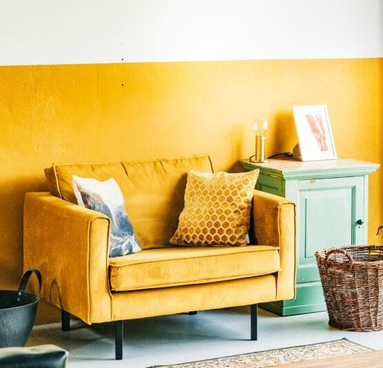 A suede loveseat with a honeycomb pattern pillow.