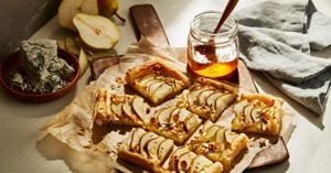 A pastry drizzled with golden honey resting on brown parchment paper.