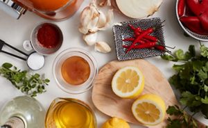Ingredients for making marinade including cutting board with lemons, honey, peppers, herbs, oil and vinegar.