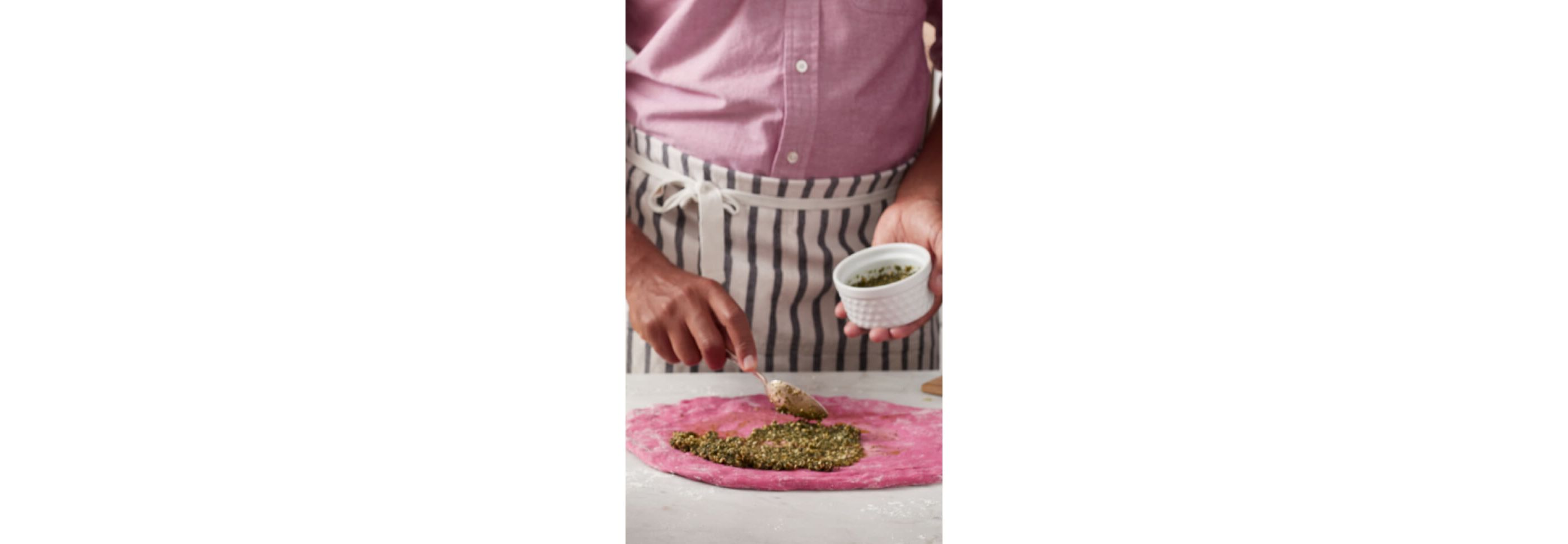 A person making Beetroot pasta with pesto sauce.