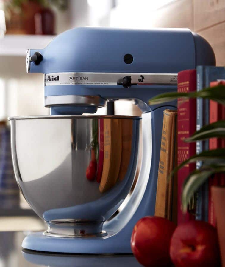 A close-up of a Blue Velvet Stand Mixer with a stainless steel bowl resting on a dark countertop.