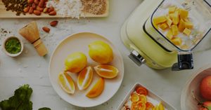 A Kyoto Glow blender filled with sliced mangos and yogurt surrounded by citruses and granola.