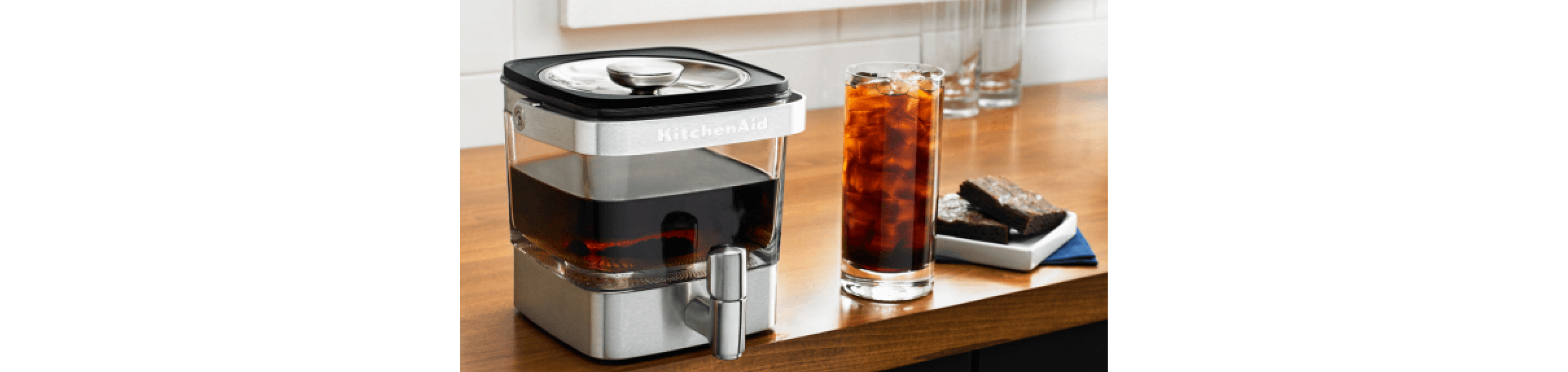 A glass of cold brew sitting next to a KitchenAid® Cold Brew Maker. 