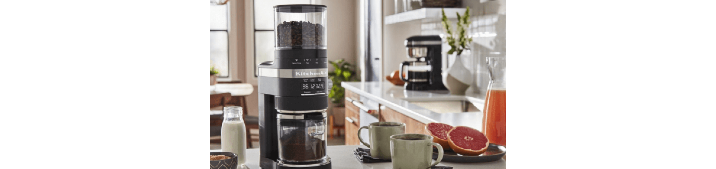 Best home coffee setup on countertop, including KitchenAid® Burr Grinder surrounded by milk, cinnamon, two cups of coffee and grapefruit.