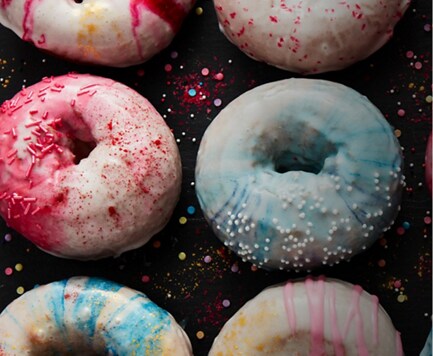 Freshly made, colorful donuts covered in sprinkles.