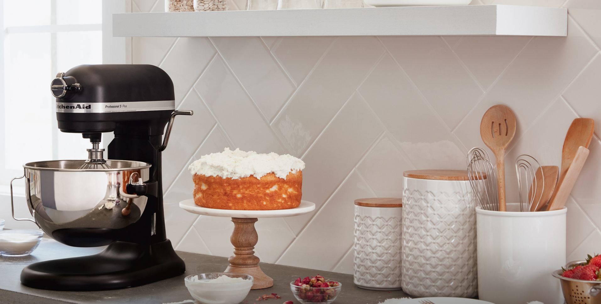 A KitchenAid® Stand Mixer on counter beside a cake