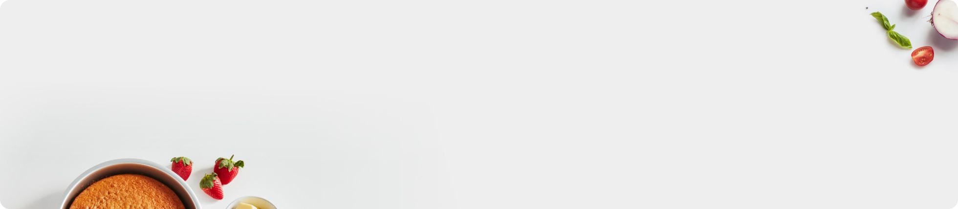 Cake in a cake tin surrounded by fruits and vegetables