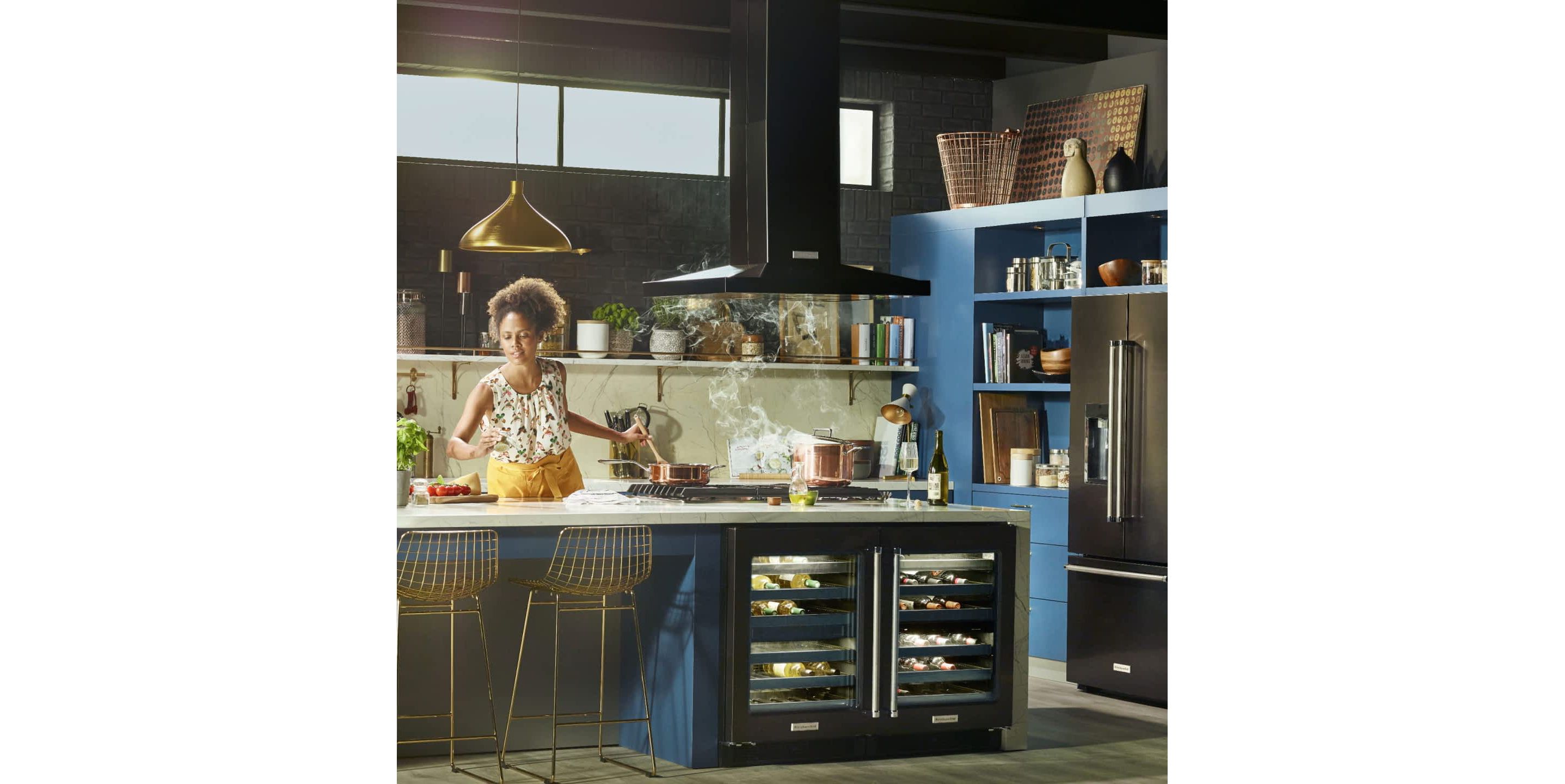 Young female Maker in a stylish, updated kitchen cooking over a pot of steaming liquid.