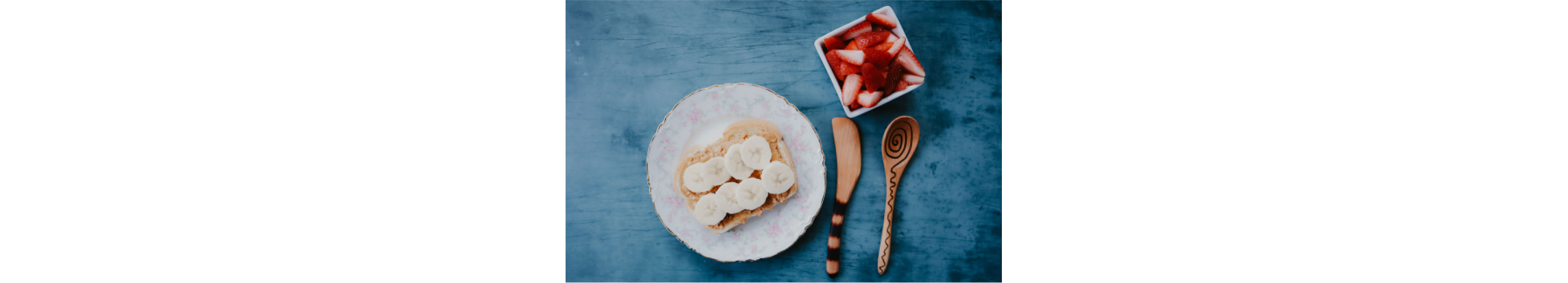 A piece of peanut butter toast with bananas and strawberries.