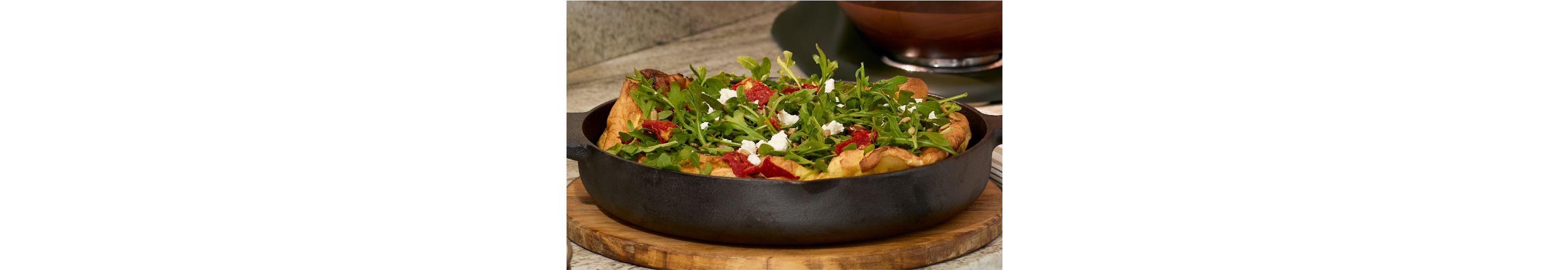 A savory dutch baby filled with a baby arugula salad.