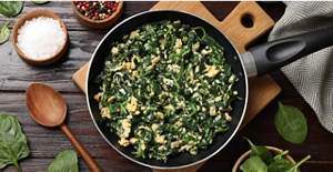 A skillet filled with cooked spinach and ground chicken.