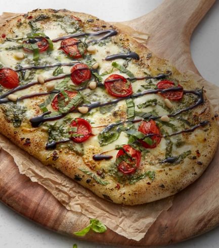 A sliced, freshly made pizza resting on a wooden cutting board.