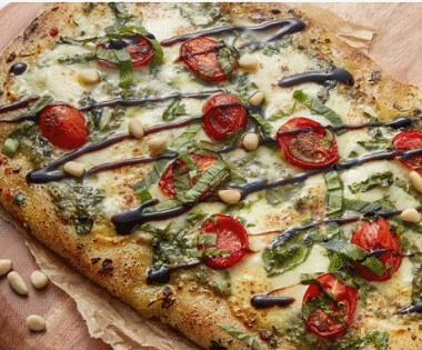 A sliced, freshly made pizza resting on a wooden cutting board.