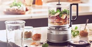 A Contour Silver KitchenAid® food chopper holding various ingredients and seasonings.