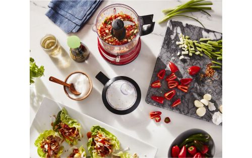 A Red KitchenAid® food chopper holding a red sweet pepper salsa for fresh lettuce wraps.