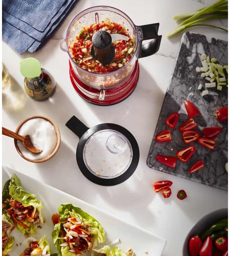 A Red KitchenAid® food chopper holding a red sweet pepper salsa for fresh lettuce wraps.