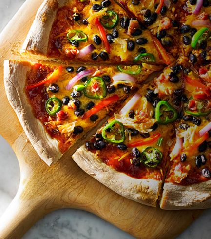 A sliced, freshly made pizza resting on a wooden cutting board.