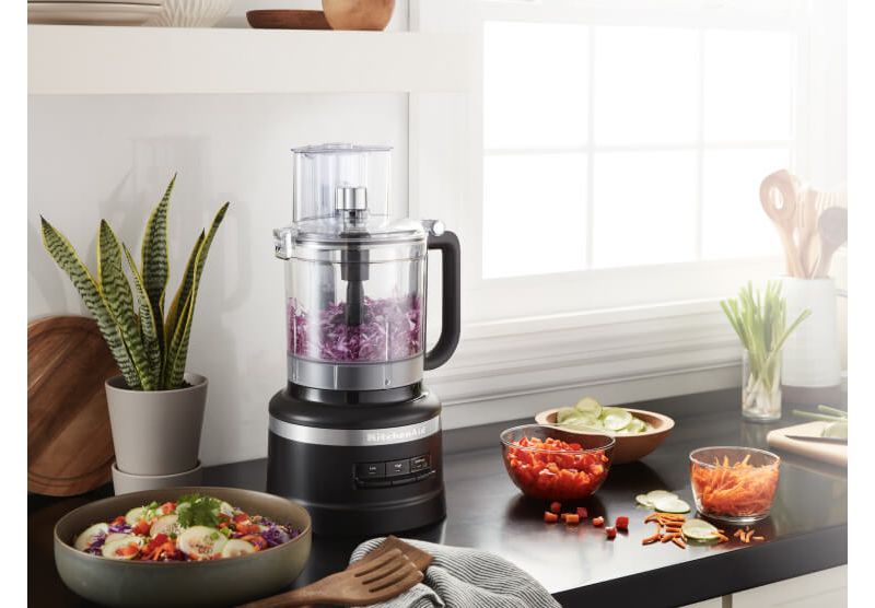 A Matte Black 13 Cup Food Processor holding red cabbage.