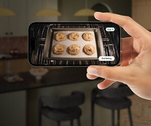 A hand holding a phone with an image of a chicken roasting in an oven