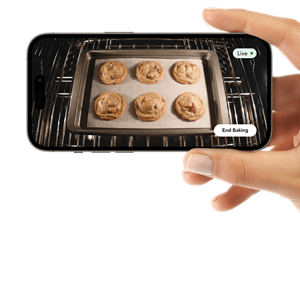A person holding a phone with a video of cookies baking in an oven