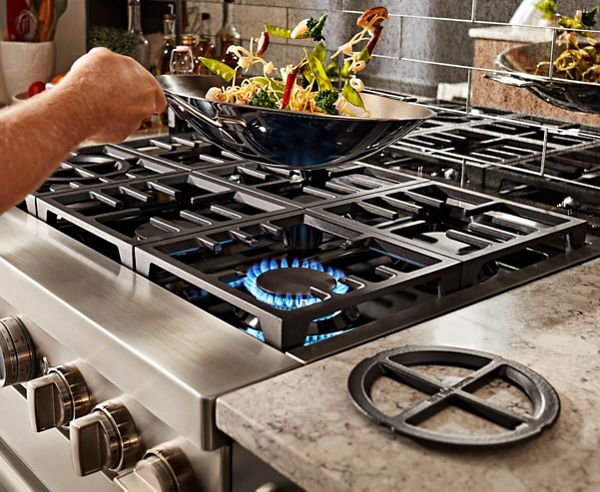 Vegetables being sauteed and tossed over a range and its flame.