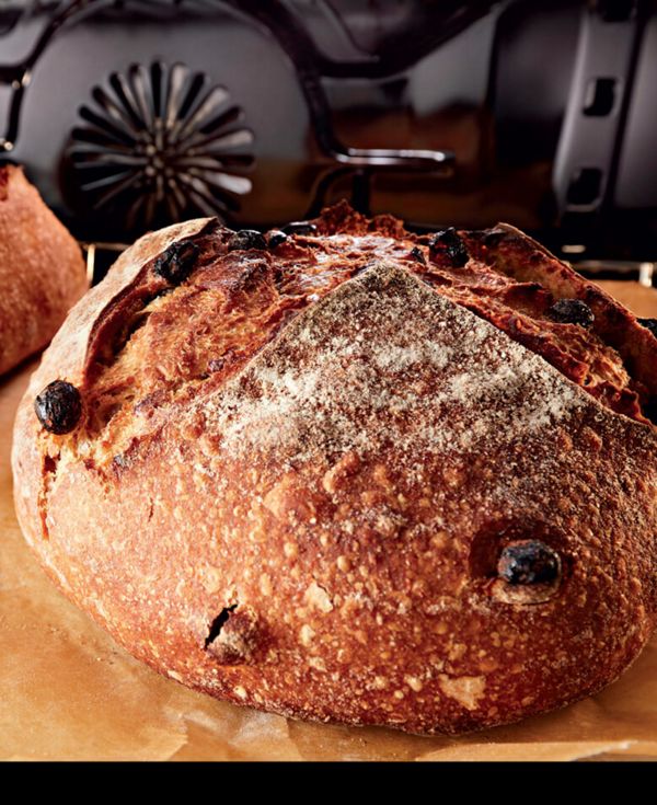 Close-up of a loaf of raisin bread being removed from oven.