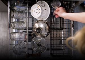 An overhead shot of a single dishwasher rack being loaded up to full capacity with various dishes.