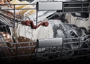 A close-up of dishes in the dishwasher dripping with water during a rinse cycle.