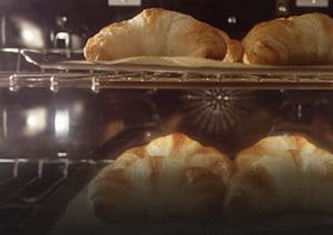 Close-up of croissants baking in convection oven.