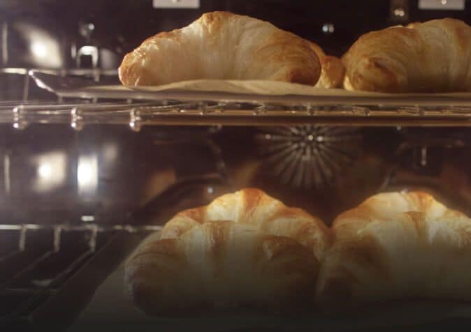 Close-up of croissants baking in convection oven.