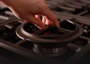 Close-up of hand placing convertible grate above burner.