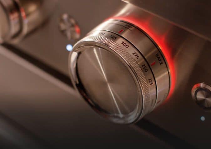 Close-up of temperature dial on a stainless steel range.
