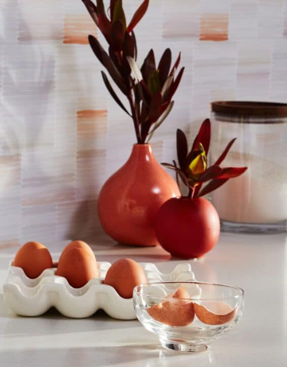 An assortment of eggs placed in front of two vases.