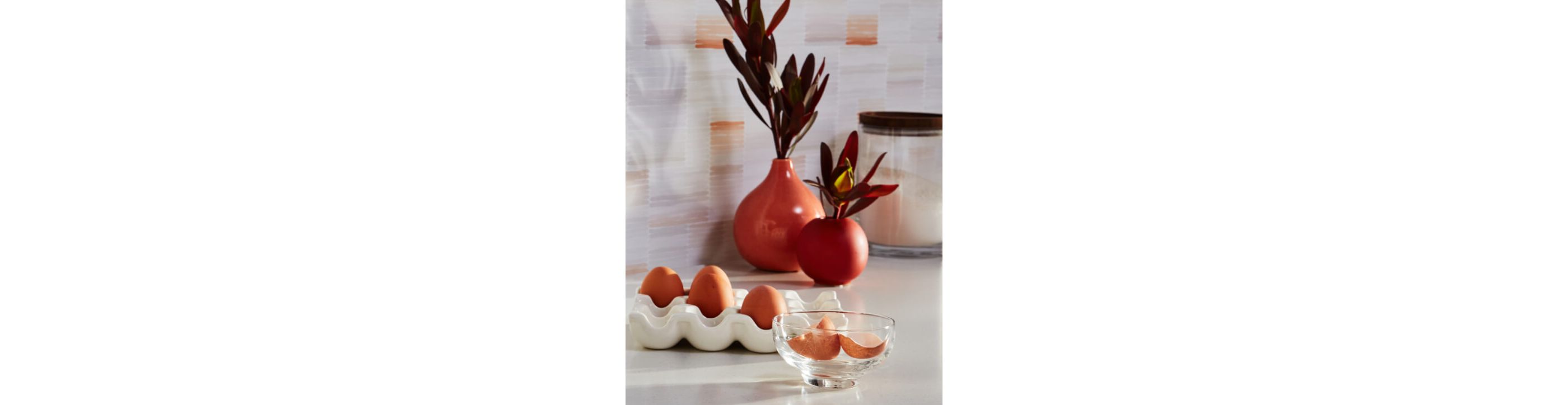 An assortment of eggs placed in front of two vases.