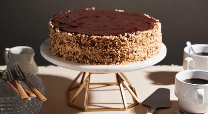 A decadent cake resting on an elevated stand.