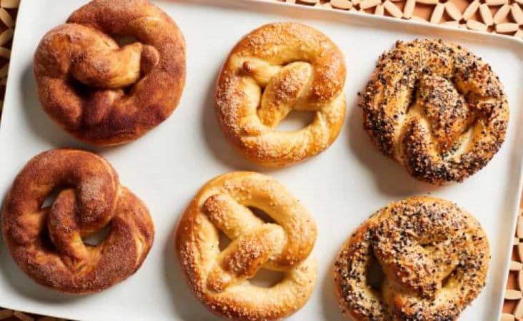 Six Buttery Soft Pretzels placed on a baking sheet.