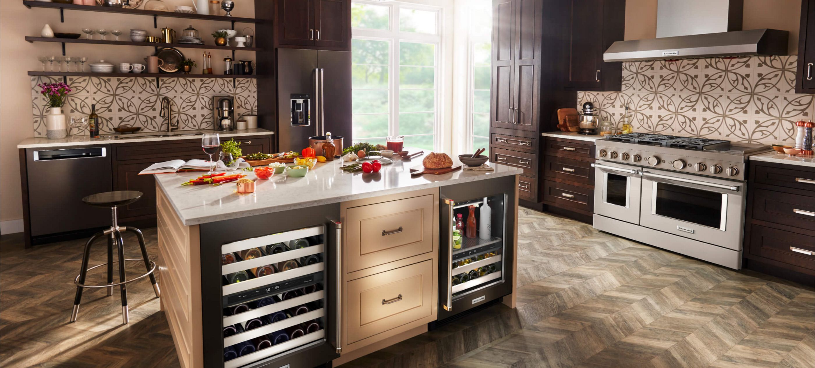 A rich, modern kitchen filled with KitchenAid® appliances and an island with different ingredients across the countertop.