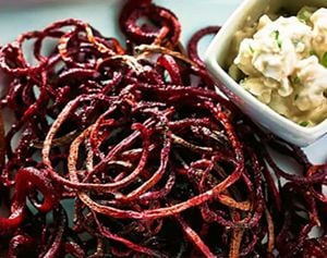 Roasted beet strings served on a plate with a balsamic goat cheese dip.